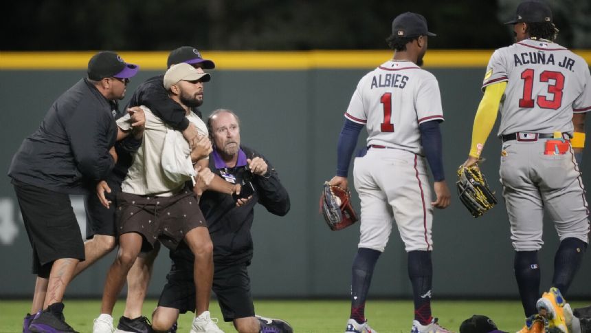 Fans run onto field and one makes contact with Atlanta Braves star Ronald Acuna Jr.