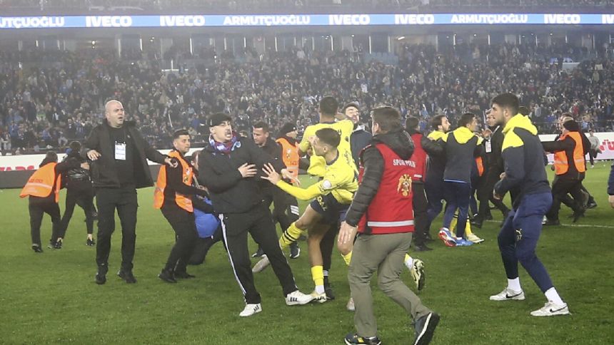 Trabzonspor fans invade pitch, attack Fenerbahce players in Turkey. Police have detained 12 people